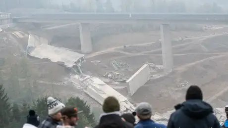 照片中几个人向山谷俯视，山谷里横亘着被炸毁的部分山谷桥