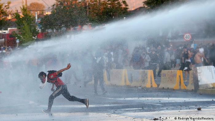 Foto de manifestante que es rociado con agua en Chile