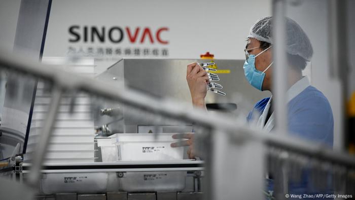 Funcionário do laboratório chinês Sinovac analisando doses numa fábrica em Pequim