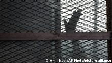 FILE - In this Aug. 22, 2015 file photo, a Muslim Brotherhood member waves his hand from a defendants cage in a courtroom in Torah prison, southern Cairo, Egypt. A leading human rights group says the coronavirus has struck several Egyptian prisons and killed several detainees, as authorities seek to stifle news of the virus’s spread behind bars. Human Rights Watch, released an extensive report Monday, July 20, 2020 documenting multiple cases of detainees who died after experiencing virus symptoms without being tested or receiving adequate medical treatment. (AP Photo/Amr Nabil, File) |