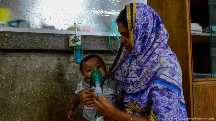 A woman holds a nebulizer on the face of her baby at a hospital in Dhaka