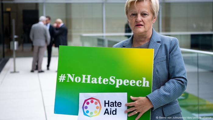 Renate Künast hält Plakate der Kampagnen #NoHateSpeech und HateAid in ihren Händen