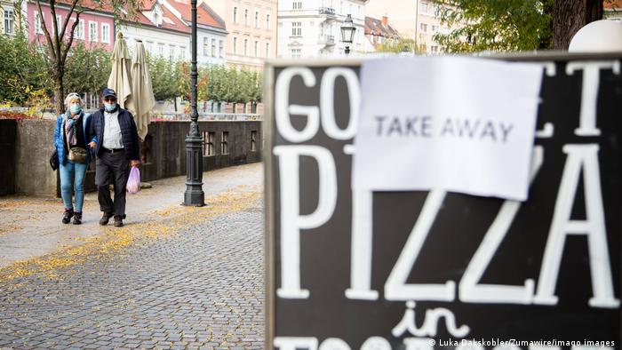 People walking past pizza takeaway sign