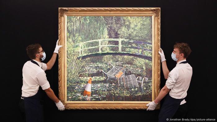 Homens seguram quadro Show me the Monet, de Banksy