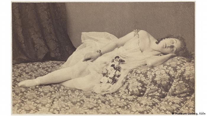 A black-and-white photo of a woman sleeping on a bed