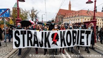 Протестующие в Польше несут транспарант: Забастовка/удар женщин
