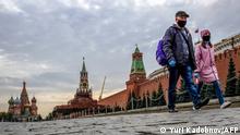 People wearing face masks and gloves to protect against the coronavirus disease walk along Red Square in central Moscow on October 10, 2020. (Photo by Yuri KADOBNOV / AFP)