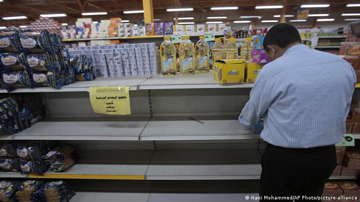 A man stands in front of partly empty supermarket shelves