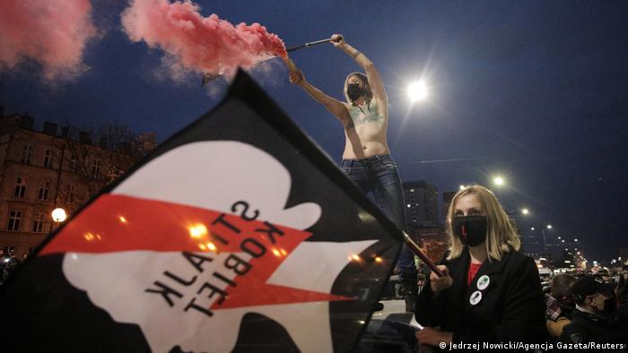 Protester in Warsaw, with a face mask and waving a flag