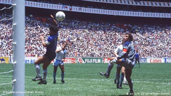 Argentina's Diego Maradona heads a soccer ball into the net as England defenders look on in a packed stadium during the 1986 World Cup in Mexico