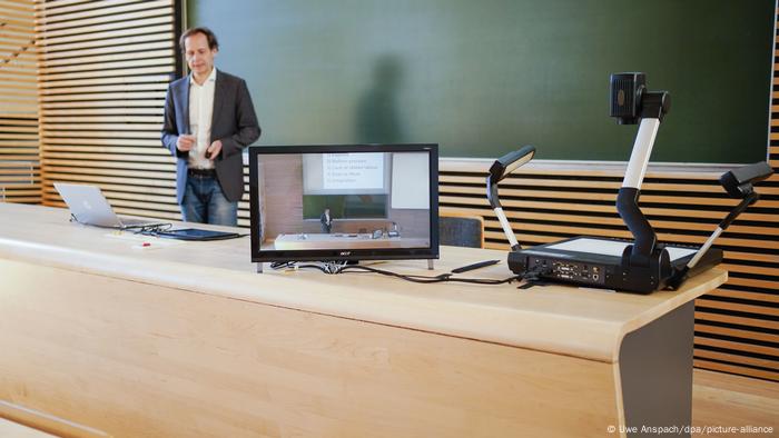 A professor giving a lecture virtually in a lecture hall A professor giving a lecture virtually in a lecture hall