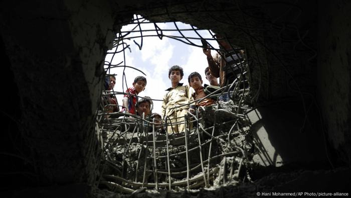 Boys look through a hole made by a Saudi-led airstrike on a bridge in Sanaa, Yemen