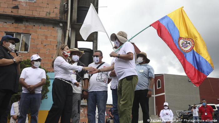 Rodrigo Granda carrying a Colombia flag shakes the hand of the sister of two kidnapping victims