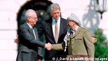 US President Bill Clinton (C) stands between PLO leader Yasser Arafat (R) and Israeli Prime Minister Yitzahk Rabin (L) as they shake hands for the first time, on September 13, 1993 at the White House in Washington DC, after signing the historic Israel-PLO Oslo Accords on Palestinian autonomy in the occupied territories. AFP PHOTO J.DAVID AKE (Photo by J. DAVID AKE / AFP) (Photo by J. DAVID AKE/AFP via Getty Images)
