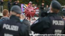 31.10.2020, Nordrhein-Westfalen, Düsseldorf: Auf dem Johannes Rau Platz stehen zwei Polizisten vor einem große Corona-Virus- Modell bei einem Protest gegen die Corona-Maßnahmen. Foto: David Young/dpa | Verwendung weltweit
