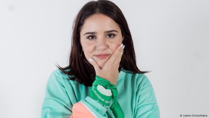 Woman with dark hair and hand on chin looks directly into camera © Julieta Christofilakis