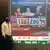 Masked man walks past screen showing US elections numbers in Mumbai 