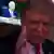 Imagem de Donald Trump desfocada em frente a televisão na qual aparece imagem de Joe Biden