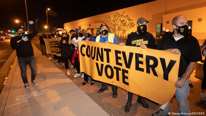 Protesters hold a sign which reads 'count every vote'