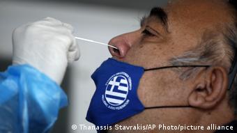 Греческий медик берет тест на коронавирус у пожилого человека