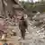 Foto de un soldado frente a una casa destruida en Nagorno Karabaj