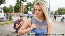 ILLUSTRATION - Ein Mann sitzt am 14.07.2017 in Hamburg auf einer Mauer und schaut einer jungen Frau hinterher, die an ihm vorbei laeuft (gestellte Szene). Foto: Christin Klose | Verwendung weltweit