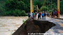 People look at the damage caused by heavy rains brought by Hurricane Eta, now degraded to a tropical storm, on a bridge over the overflooded Cahaboncito river in Panzos, Alta Verapaz, 220 km north of Guatemala City on November 6, 2020. - About 150 people have either died or remain unaccounted for in Guatemala due to mudslides caused by powerful storm Eta, which buried an entire village, President Alejandro Giammattei said Friday. (Photo by Johan ORDONEZ / AFP) (Photo by JOHAN ORDONEZ/AFP via Getty Images)