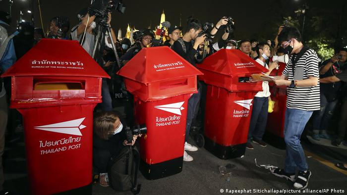 A Thai protester puts a letter in a red mailbox in Bangkok