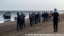 dpatopbilder - ARCHIV - 21.10.2020, Spanien, Gran Canaria: Migranten aus Marokko gehen in Begleitung der spanischen Polizei am Strand entlang, nachdem sie mit einem Holzboot an der Küste von Gran Canaria angekommen sind. Etwa 1000 Migranten haben wieder in Notzelten auf einem Dock übernachtet, während sich die Behörden auf den Kanarischen Inseln darüber beschweren, dass die spanische Regierung wegen Coronavirus-Bedenken weiterhin den Transfer neu angekommener Migranten auf das Festland blockiert. (zu dpa: EU-Innenkommissarin betont auf Kanaren Kampf gegen Menschenschmuggler) Foto: Javier Bauluz/AP/dpa +++ dpa-Bildfunk +++