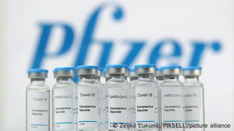 Ампулы с вакциной от коронавируса на фоне логотипа компании Pfizer