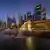 Die beleuchtete Skyline von Singapur mit dem Wasser speienden Merlion, dem Wahrzeichen der Stadt, im Vordergrund