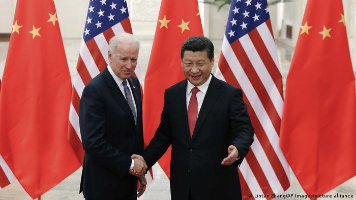  Xi and Biden shake hands amid the alternating flags of the United States and China