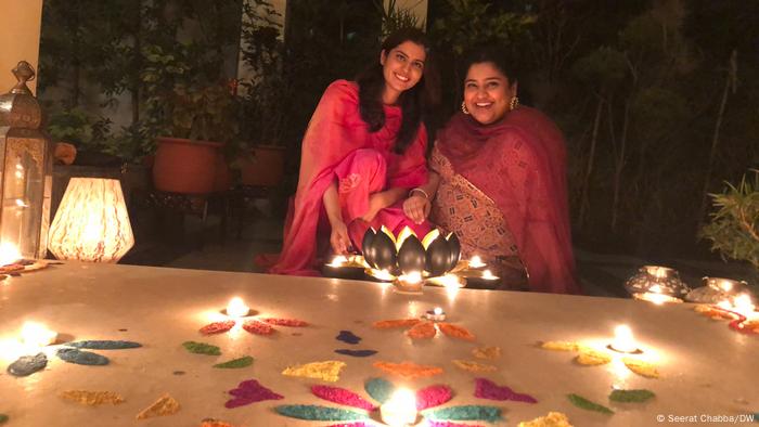 Two young women pose with their rangoli, a sacred pattern drawn on floors during auspicious occasions like Diwali (Seerat Chabba/DW)