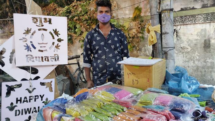 A young man spends his evening waiting for customers to finish their last-minute shopping ahead of Diwali (Seerat Chabba/DW)