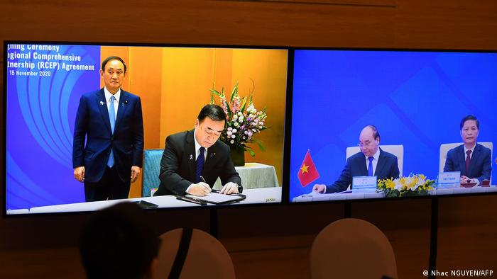 In Tokio signiert der japanische Handelsminister Hiroshi Kajiyama. Links Ministerpräsident Yoshihide Suga. Auf dem Monitor rechts die jeweiligen vietnamesischen Kollegen (Foto: Nhac NGUYEN/AFP)