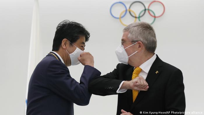 Shinzo Abe in a facemask greets with elbows amid pandemic