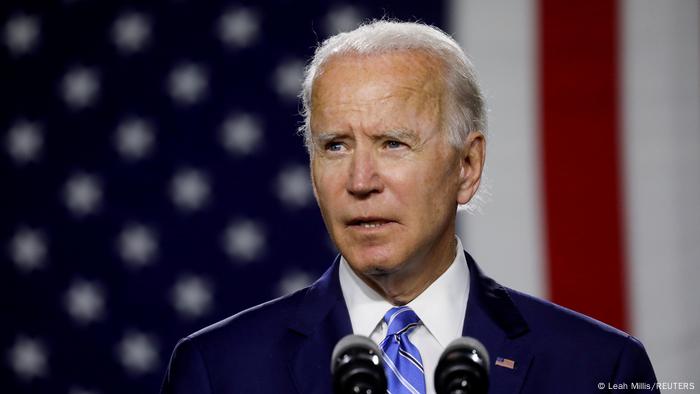 A photo of Joe Biden in front of an American flag