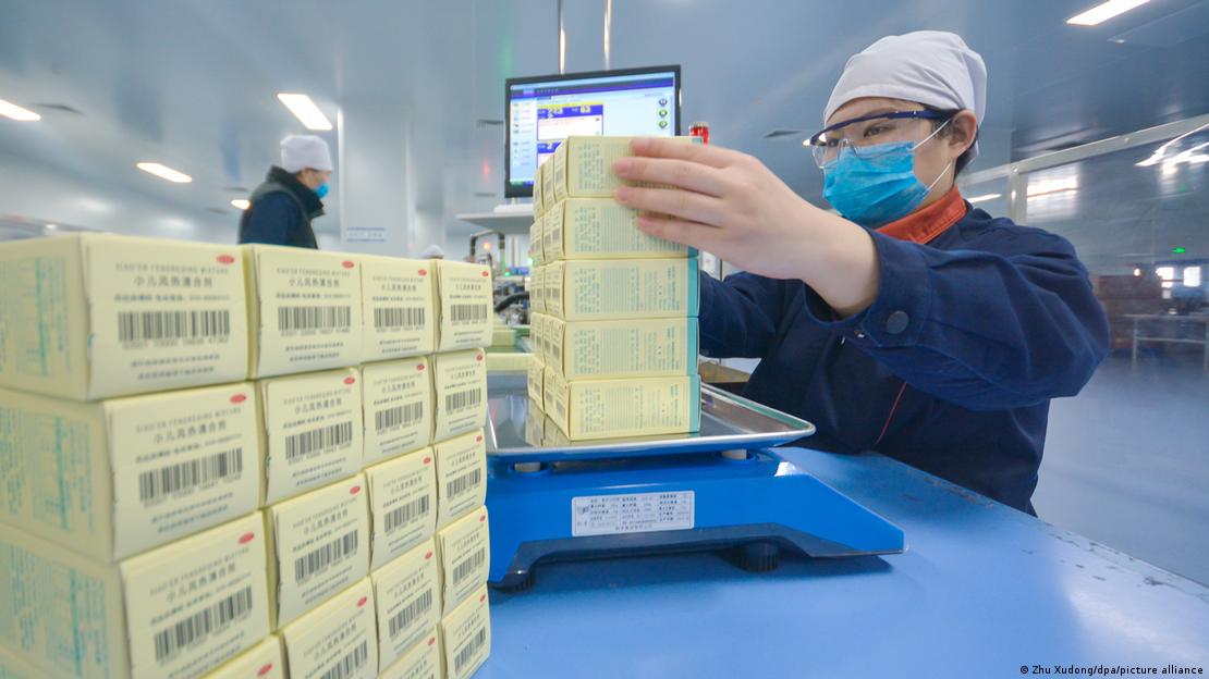 Mulher pesa pacotes de remédios em indústria na China Mulher pesa pacotes de remédios em indústria na China