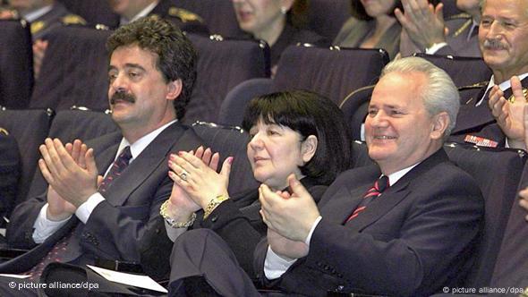 Slobodan Milosevic (right), his wife, Mirjana Markovic (center), and the Yugoslav Prime Minister Momir Bulatovic (left) clap as they sit in a hall at an event celebrating the army, June 15, 1999