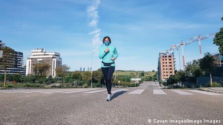 Woman wearing a mask and jogging through a city