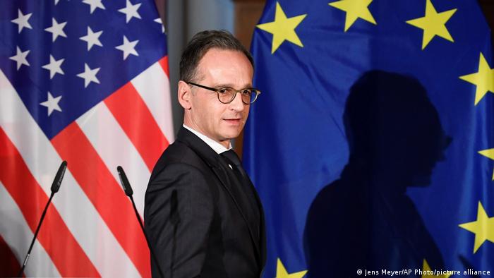 German Foreign Minister Heiko Maas stands in front of US and EU flags