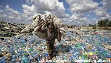A man walks on a mountain of plastic bottles as he carries a sack of them to be sold for recycling after weighing them at the dump in the Dandora slum of Nairobi