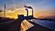 Solar panels in the foreground and chimney stacks puffing smoke in the background Solar panels in the foreground and chimney stacks puffing smoke in the background