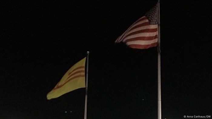 In the middle of the parking lot at the Eden Center in Falls Church, Virginia, hang the flags of the US and South Vietnam, a country that ceased to exist with the fall of Saigon in 1975