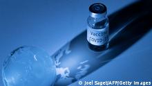 An illustration picture taken on November 19, 2020, shows a vial with Covid-19 Vaccine sticker and an earth globe. (Photo by JOEL SAGET / AFP) (Photo by JOEL SAGET/AFP via Getty Images)
