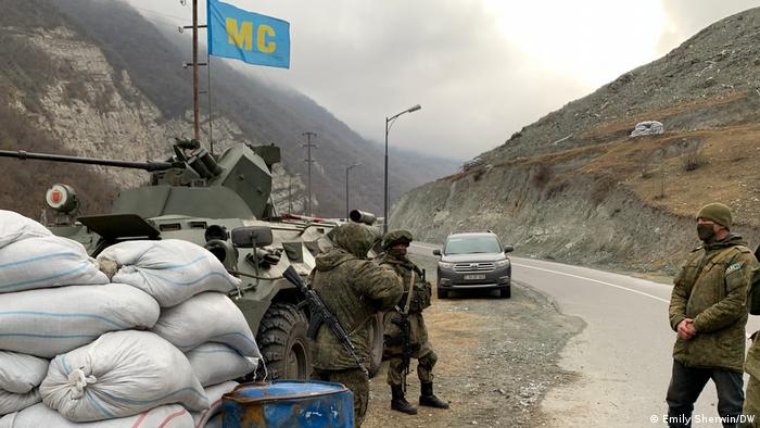 Russian peacekeepers stand next to a tank on the side of the road in the Kalbajar district