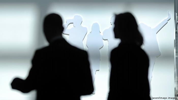 A stock photo showing the silhouettes of a male and female business professional 