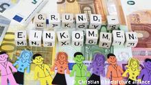 Buchstabenwürfel formen das Wort Grundeinkommen auf Geldscheinen | Verwendung weltweit