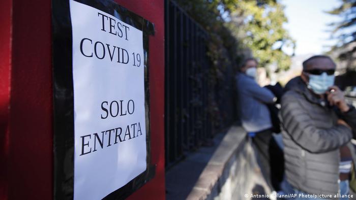 Foto de una persona en Italia con mascarilla que se acerca a un establecimiento con tests de COVID-19