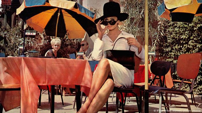 Sophia Loren mit Hut, Handtasche und Sonnenbrille an einem Tisch